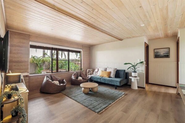 A spacious living room with a large window, a sofa, a coffee table, and a TV.