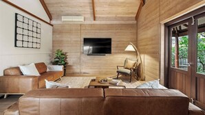 A modern living room with a wooden ceiling, a flat-screen TV, a sofa, a chair, and a coffee table. - Pepperstone—Serene Coastal Hideaway with Fire Pit (Dunsborough)