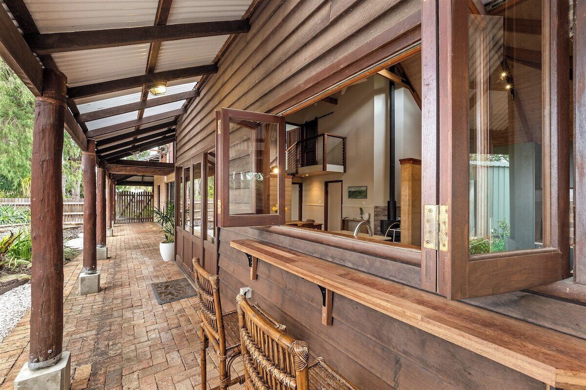 A covered outdoor area with wooden benches and a brick pathway.