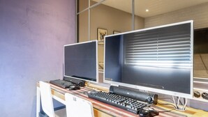 A workspace with two monitors, a keyboard, and a mouse on a desk. - NU Hotel (Cheonan)