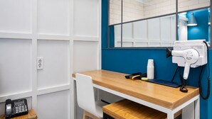 A hotel room with a wooden desk, a hairdryer, a telephone, and a mirror. - NU Hotel (Cheonan)