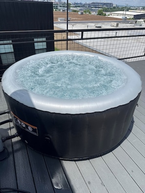 A hot tub on an outdoor deck with a cityscape view.
