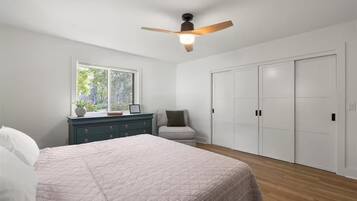 A bedroom with a bed, a dresser, a chair, a window, and a closet.