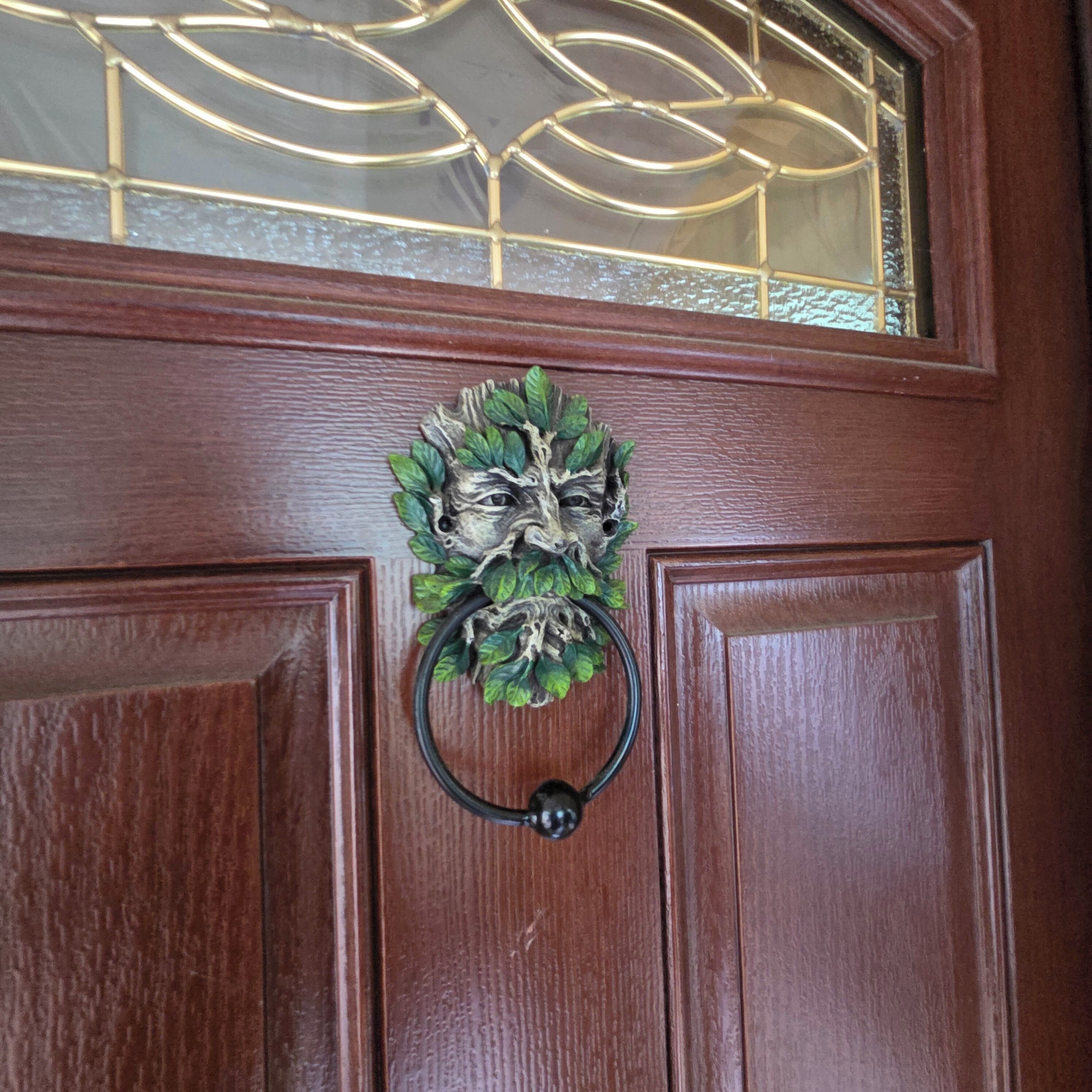 A wooden door with a metal knocker and a decorative wreath.