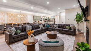 Ein modernes Wohnzimmer mit einem Ecksofa, einem Couchtisch und einem Essbereich mit Stühlen.