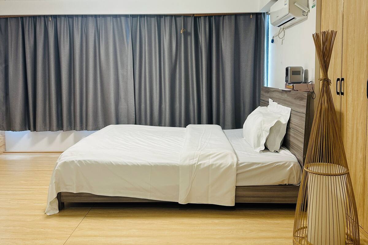 Une chambre moderne avec un grand lit, un plancher en bois, une armoire et un ventilateur de plafond.