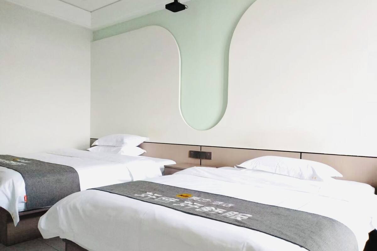 Une chambre d’hôtel avec deux lits, un design moderne et un luminaire fixé au mur.