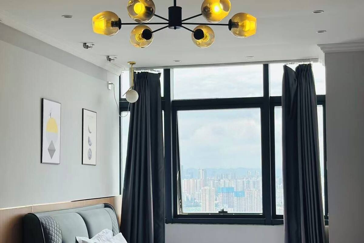 Une chambre d’hôtel moderne, équipée d’un lit, d’un canapé, d’une table basse et d’une grande fenêtre avec des rideaux.