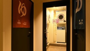 A hotel entrance with a men's and women's restroom sign, a washing machine, and a towel rack. - HOTEL LiVEMAX Nara Ekimae (Nara)