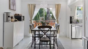 Una cucina moderna con zona pranzo, caratterizzata da un'isola centrale, un lampadario e vista sull'esterno.