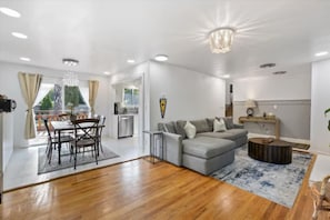 Un salon spacieux avec un canapé gris, un plancher en bois et un coin repas comprenant une table et des chaises.