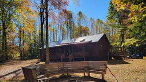 A rustic cabin with a porch, surrounded by autumn trees. - Privacy & nature with Hot Tub, Fireplace, fire pit, & local outdoor activities, (Mount Lookout)