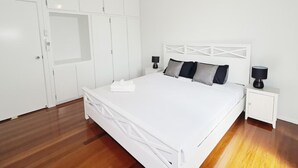 A bedroom with a white bed, a nightstand, a ceiling fan, and a wardrobe. - Modern 2BR in Highgate Hill near Brisbane CBD (Highgate Hill)
