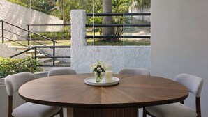 A round wooden dining table with a white candle and flowers on a tray, surrounded by four upholstered chairs. - Panoramic Paradise Above Puerto Vallarta. Infinity Pool over Romantic Zone
 (Puerto Vallarta)