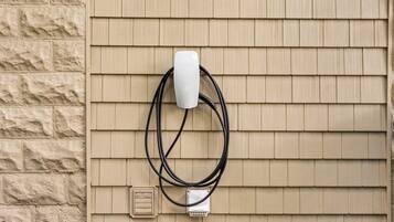 A wall-mounted electrical outlet with a white plug and a black cable.