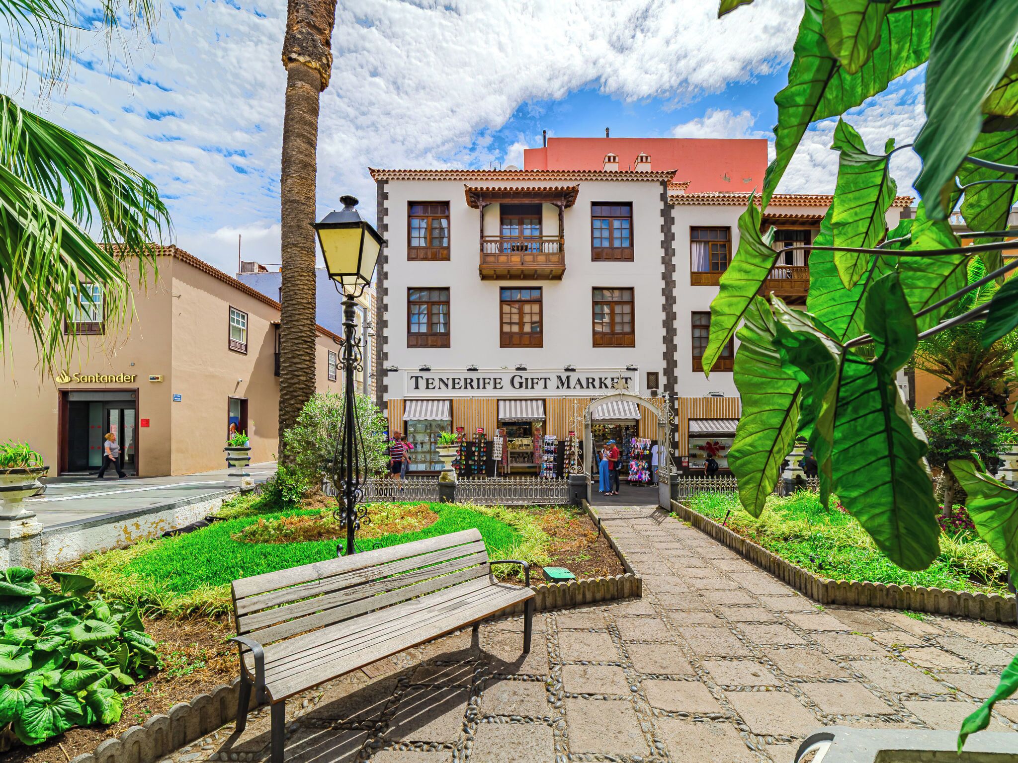 Une place avec un banc, un marché où l’on vend des souvenirs et un bâtiment avec une enseigne.
