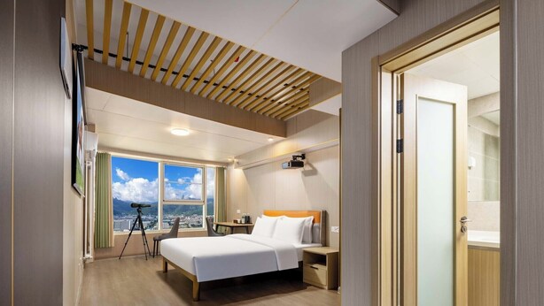 A modern hotel room with a large bed, a desk, and a telescope by the window. - Wonderful Beginning (Tai'an)