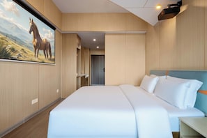 Une chambre d’hôtel avec un grand lit, une tête de lit, une table de chevet et un téléviseur fixé au mur qui diffuse une image de cheval.