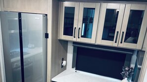 Une cuisine moderne dotée d’un réfrigérateur encastré, d’un grand plan de travail et de meubles de rangement en bois.