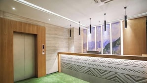 Un hall d’hôtel avec un comptoir d’accueil, une moquette verte, des lambris en bois et un mur orné de motifs.
