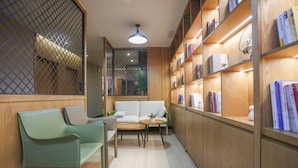 Un coin lecture confortable, avec un canapé, des fauteuils et une petite table, le tout entouré d’étagères à livres.