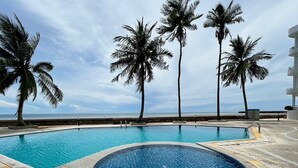 A swimming pool with a circular hot tub, surrounded by palm trees and a view of the ocean. - Seaview 2beds in the heart of HuaHin BP2 (Hua Hin)