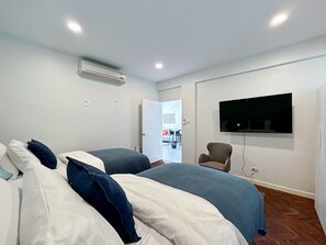 A hotel room with two beds, a TV mounted on the wall, and an air conditioning unit. - Seaview 2beds in the heart of HuaHin BP2 (Hua Hin)