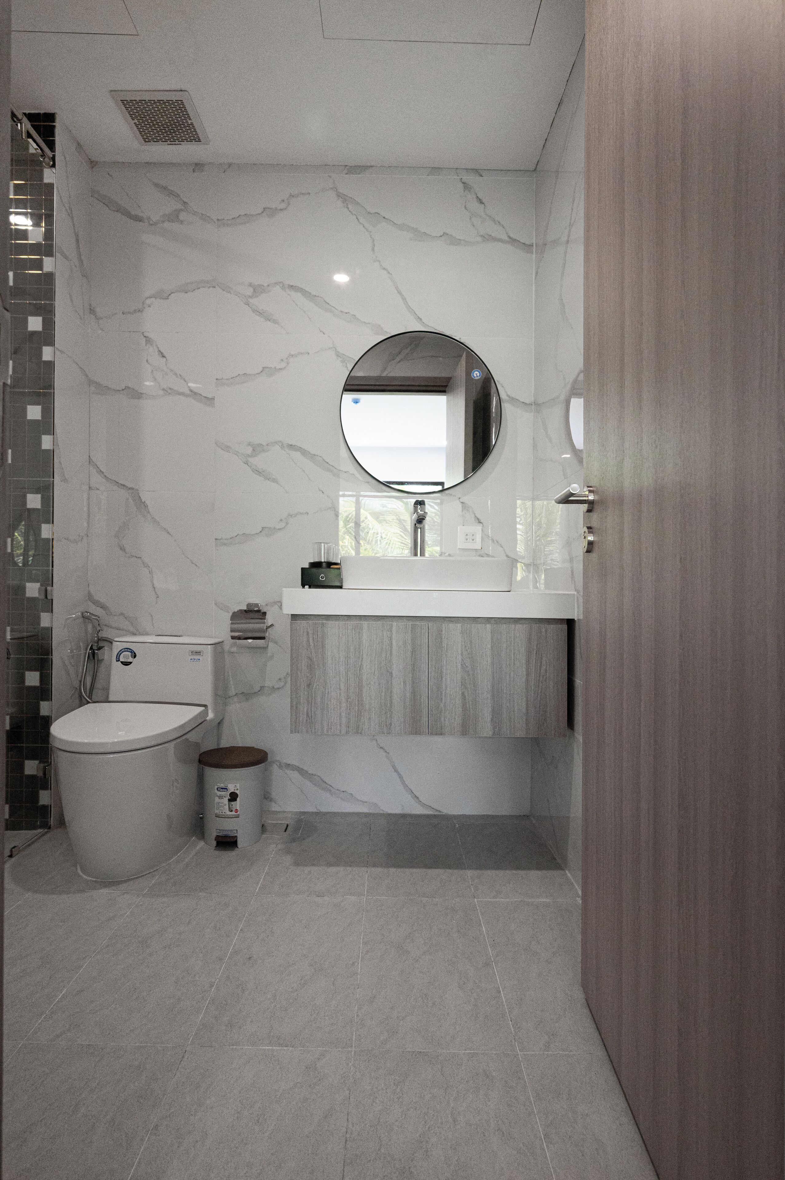 A modern bathroom with a toilet, sink, and mirror.