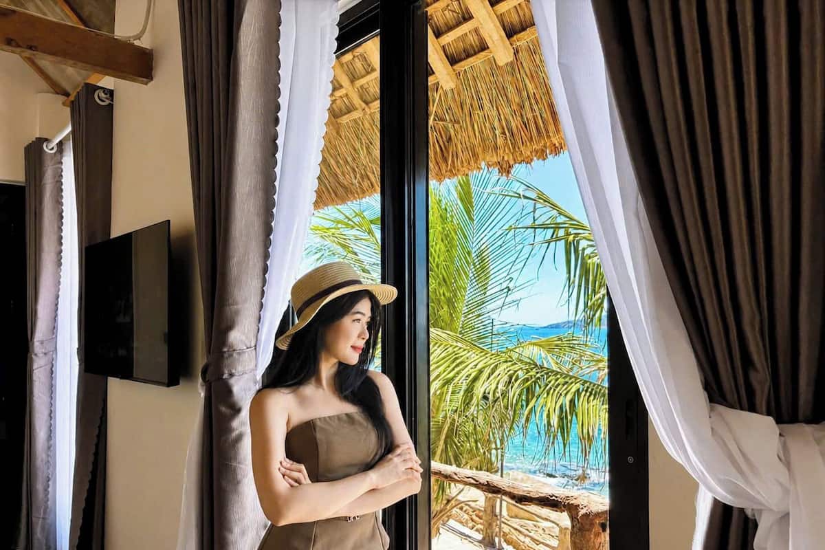 A room with a large window, a television on the wall, and a view of a beach.