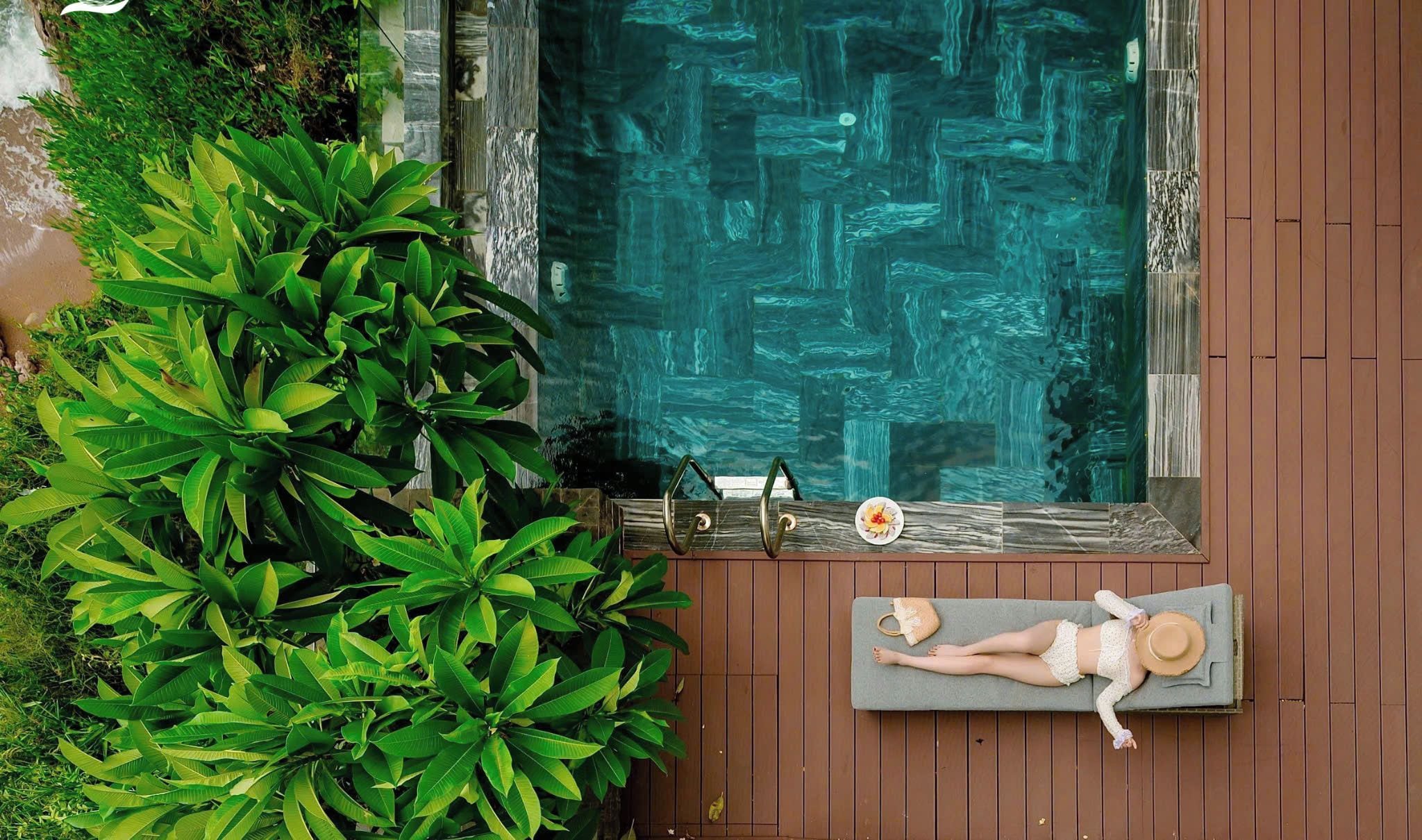 Un espace aménagé au bord de la piscine, avec un fauteuil de relaxation, une table à manger où est disposée une assiette de nourriture, et une végétation luxuriante.