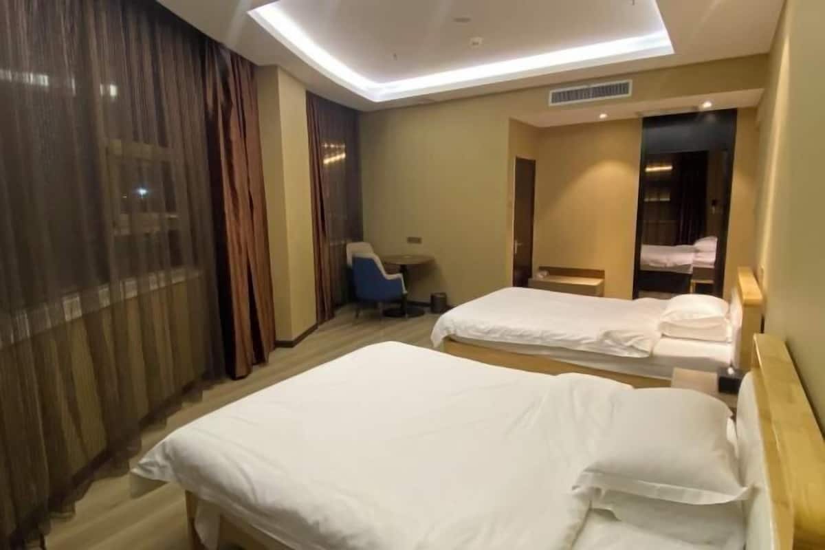 A hotel room with two beds, a desk, and a chair.