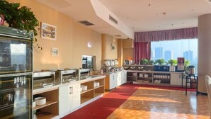 Un comedor de hotel con barra libre, un ventanal con vistas a la ciudad y una alfombra roja.