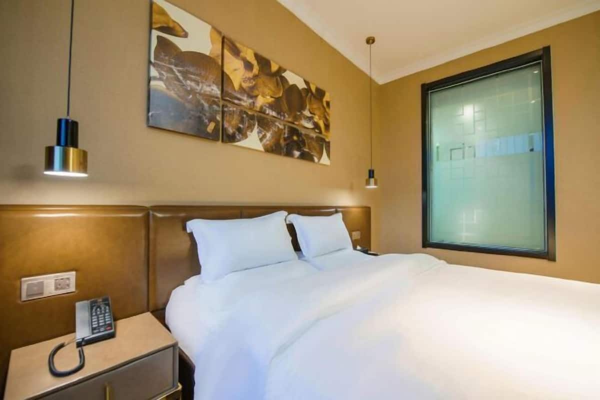 A hotel room with a bed, bedside table, and a large window.