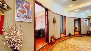 Un vestíbulo de hotel con suelo de madera, un cartel en la pared y un jarrón de flores.