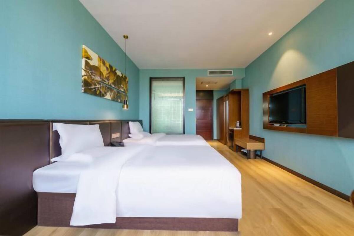 A hotel room with a large bed, a TV mounted on the wall, and a door leading to a bathroom.