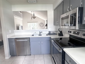 A modern kitchen with stainless steel appliances, grey cabinets, and a dishwasher.