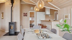 A modern interior with a central dining table, a wood-burning stove, and a kitchen area. - "Terne" - 90m from the sea by Interhome (Nykøbing Sj)