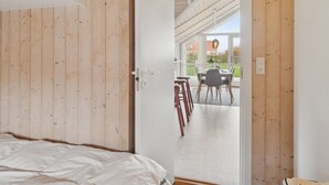 A bedroom with a wooden ceiling, a bed, and a white door leading to a balcony with a table and chairs. - "Terne" - 90m from the sea by Interhome (Nykøbing Sj)