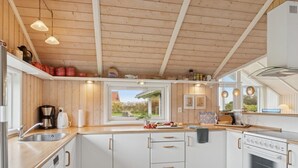 A modern kitchen with white cabinets, a wooden countertop, and a built-in oven. - "Terne" - 90m from the sea by Interhome (Nykøbing Sj)