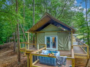 Une petite cabane en bois d’un seul étage, dotée d’une terrasse et d’un jacuzzi, et entourée d’arbres.