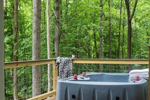 Een hottub op een terras met uitzicht op een bos.