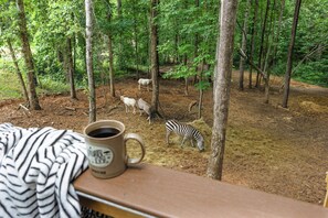 Een bebost gebied met een koffiekop op een houten oppervlak, een zebra en verschillende herten.