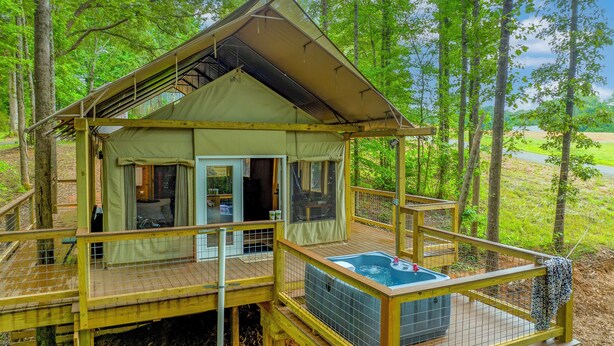 Een tentlodge met terras, een jacuzzi en uitzicht op het bos.