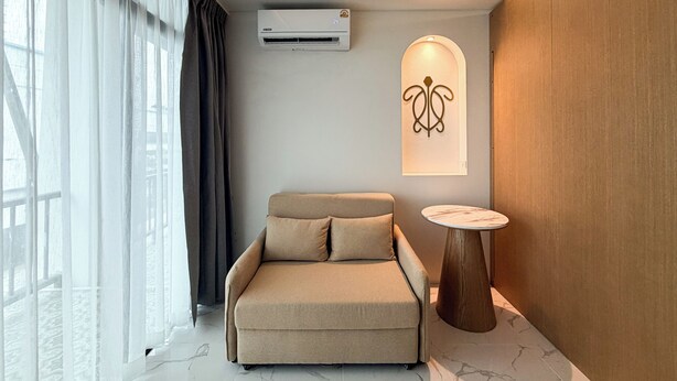 Una habitación moderna con sofá, una mesita redonda y aire acondicionado instalado en la pared.