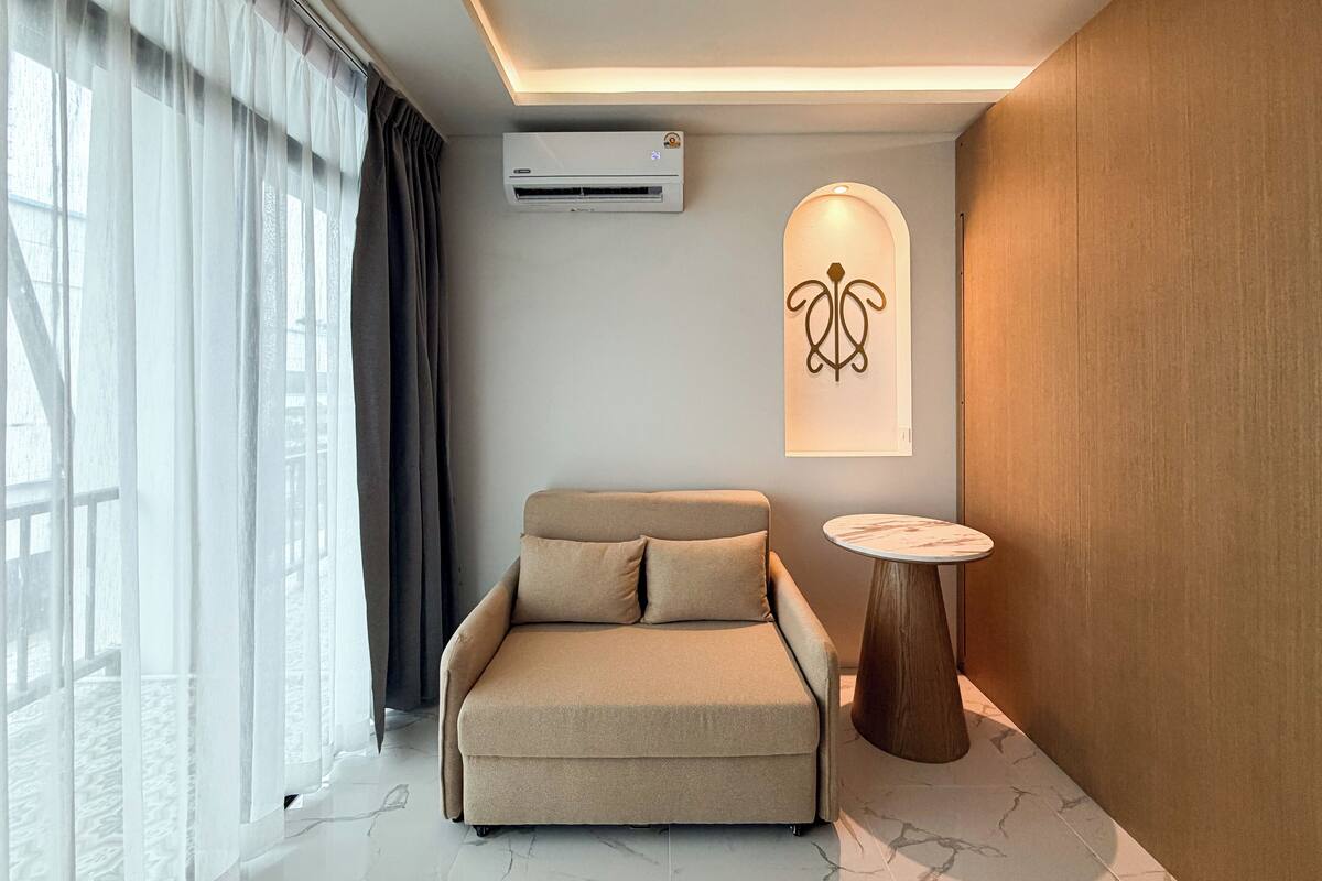 Una habitación moderna con sofá, una mesita redonda y aire acondicionado instalado en la pared.