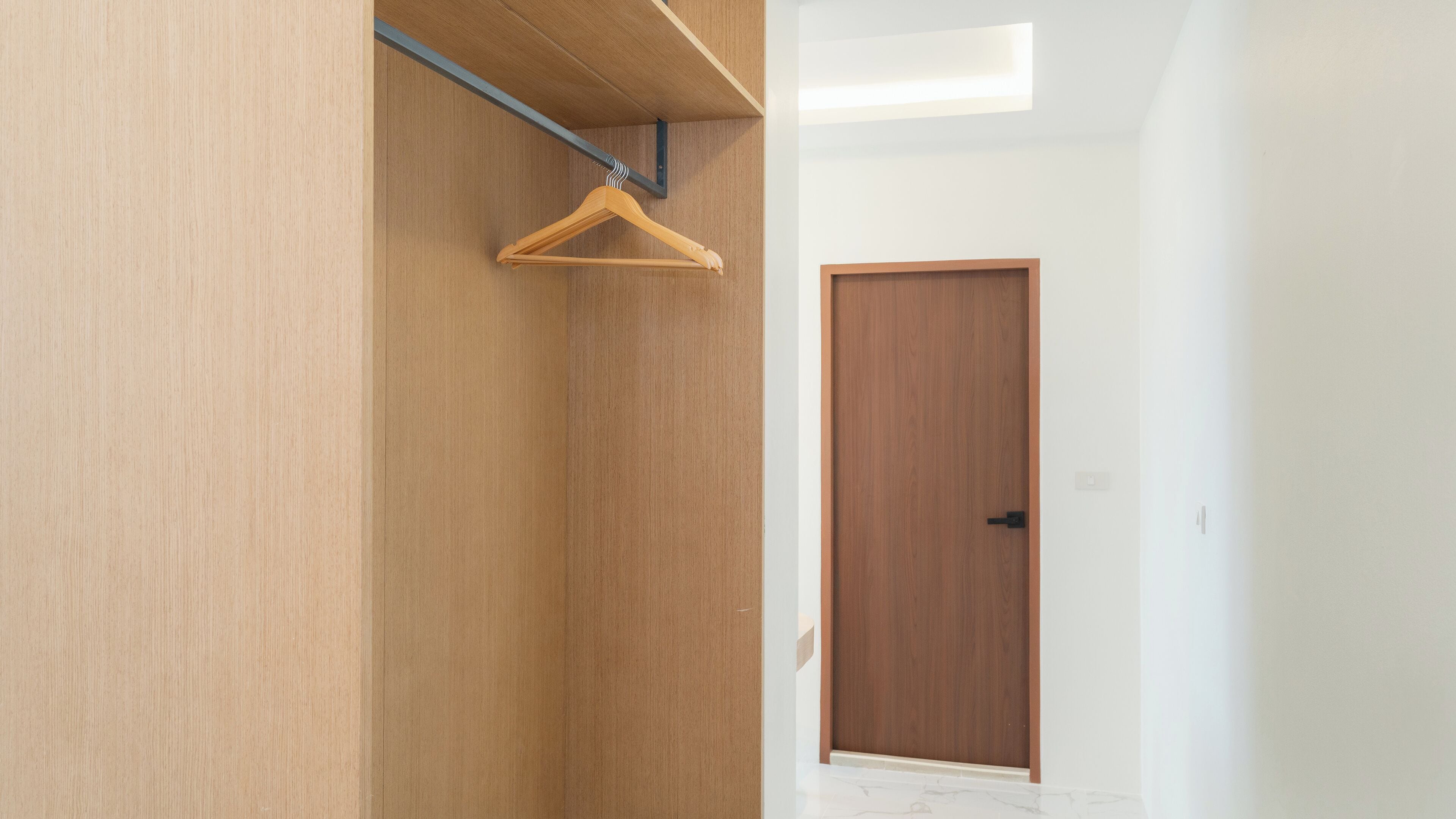 A hallway with a wooden wardrobe, a wooden door, and a hanging wooden hanger.