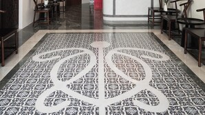 Un hall de hotel con piso estampado, una recepción y un techo con iluminación empotrada.
