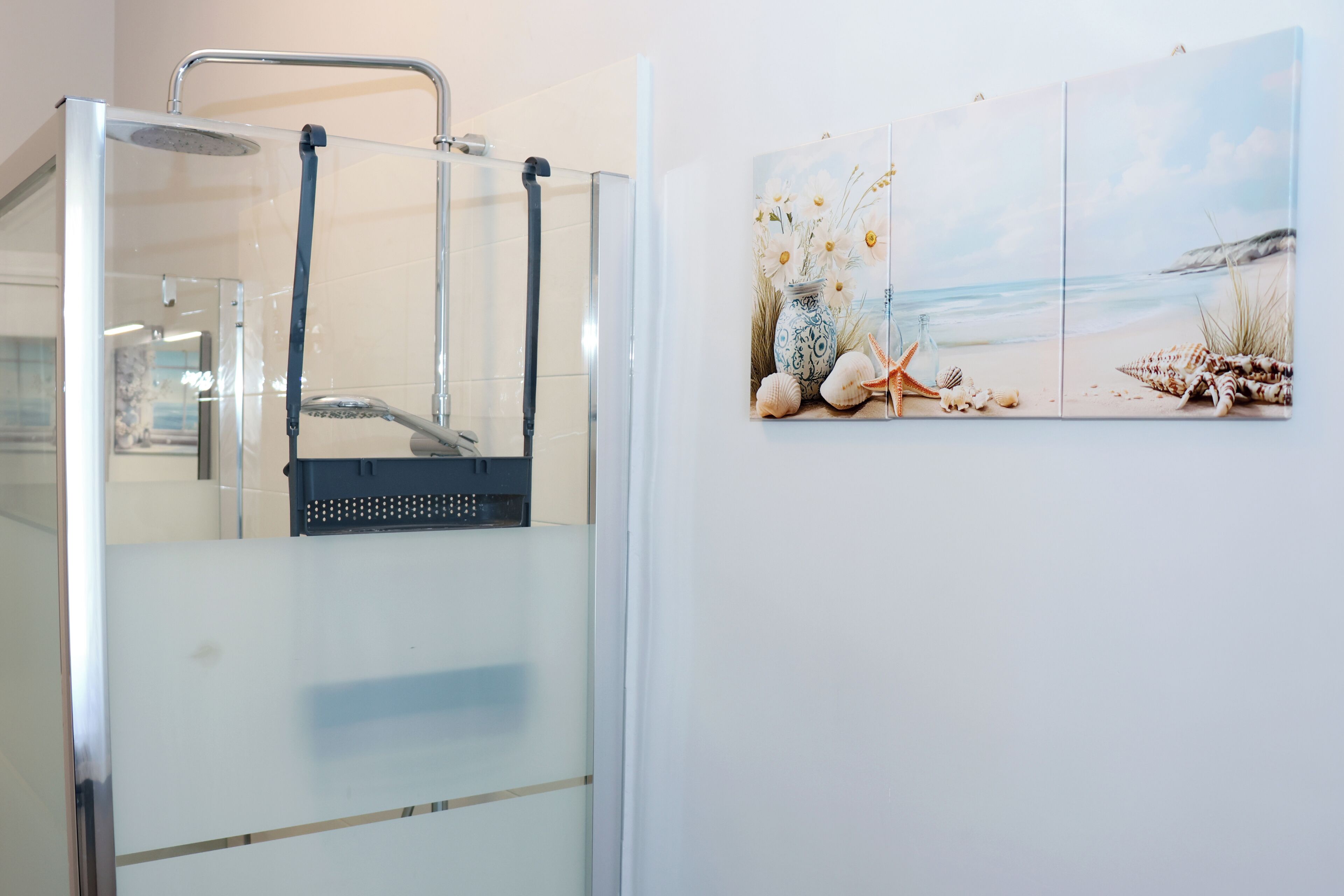 A shower with a glass door, a towel rack, and a wall-mounted towel dispenser.