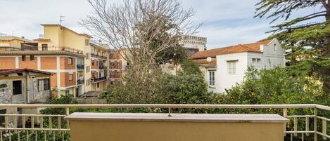 Un quartier résidentiel avec des immeubles à plusieurs étages, un balcon doté d’une balustrade et un arbre au premier plan.