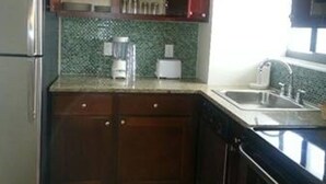 A kitchen with wooden cabinets, a refrigerator, a sink, and a tiled backsplash. - Pompano Beach FL - Oceanfront Condos ~ 1 Bdrm $1399/Week, Studio $995/Week (Pompano Beach)